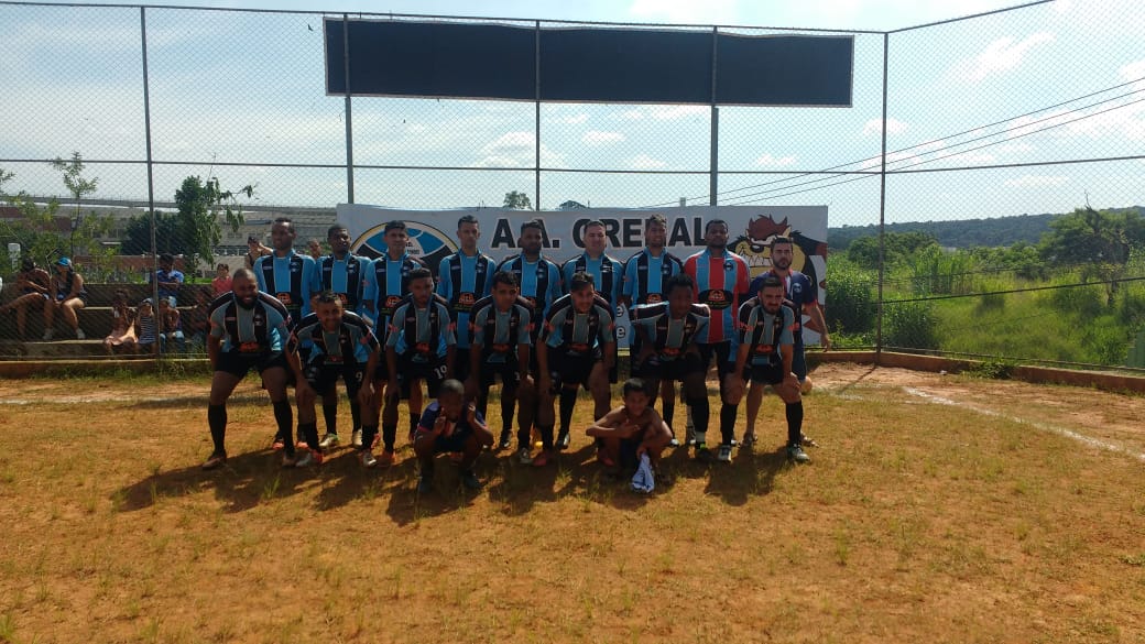 Os jogadores do time Grenal posados para a foto no meio do campo, com uniforme azul e preto.